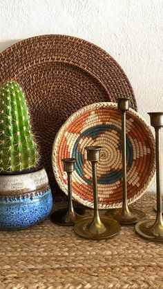 there is a basket and some candles on the table next to each other with a cactus in it