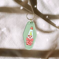 a green keychain with an image of a christmas tree and presents on it