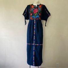 Great Pre-Owned Condition, No Defects Other Than Some Minor Signs Of Use. Beautiful Vintage Circa 1970s Guatemalan Huipil-Style Maxi Folk Dress, In A Dark Indigo Blue With Colorful Woven Designs. It Has A Pull-On Fit With No Closures, And A Low Waist With An Attached Tie - When You Tie It At The Back Of Your Natural Waist, It Cinches Up The Bodice For A Blouson Effect. It Has Half-Length Dolman Sleeves That Cinch, A Notched Neckline That Lies Open, And Pleating On The Front Of The Skirt. Mannequ Blue Embroidered Maxi Dress With Intricate Details, Blue Maxi Embroidered Dress With Intricate Embroidery, Blue Maxi Embroidered Dress With Intricate Details, Vintage Blue Embroidered Dresses, Blue Folk Dress For Spring, Blue Maxi Dress With Floral Embroidery And Short Sleeves, Blue Short Sleeve Maxi Dress With Floral Embroidery, Blue Festival Dresses With Embroidered Hem, Festival Blue Dress With Embroidered Hem