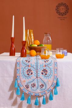 a table topped with oranges and juice on top of a white table cloth