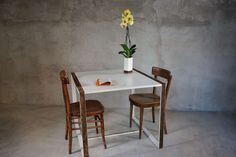 a white table with two chairs and a flower in a vase