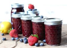 jars filled with blueberries and strawberries sit on a table