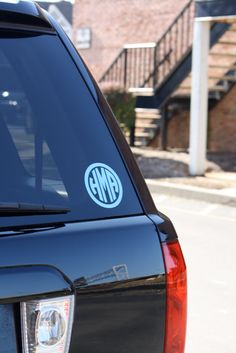 the back end of a black car with a blue and white monogrammed sticker on it