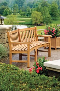 a wooden bench sitting in the middle of a garden next to some bushes and flowers