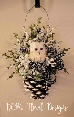 an owl head hanging from the side of a wall with pine cones and greenery