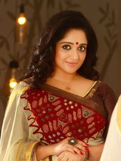 a woman in a red and white sari with her hand on her hip looking at the camera