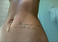 the back of a woman's stomach with words written on it and a gold chain