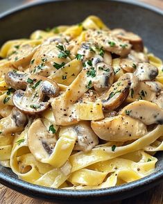 pasta with mushrooms and parsley in a blue bowl on a wooden table top, ready to be eaten