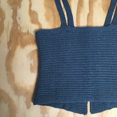 a crocheted blue top is laying on a wooden surface with the bottom part missing