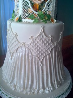 a three tiered white cake with flowers on it's side and an image of a woman in a basket