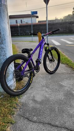 a purple bike leaning against a pole on the sidewalk