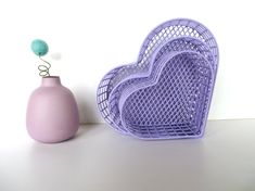 two purple heart shaped baskets next to a pink vase