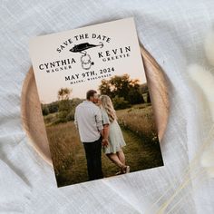 a save the date card on a wooden plate with some dried grass in front of it