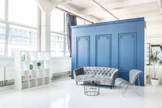 a living room filled with furniture next to tall windows and lots of bookshelves