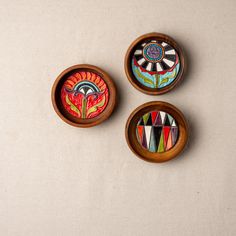 three wooden bowls with designs painted on them