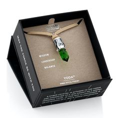 a green necklace in a black box with the words yoda on it and an arrow