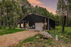 a large black barn sitting in the middle of a forest