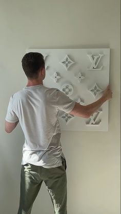 a man in white shirt and khaki pants working on a wall