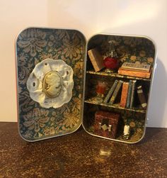 an open tin can with some books and other items in it on a table next to a wall