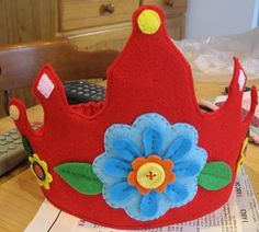 a red felt crown sitting on top of a wooden table next to a remote control