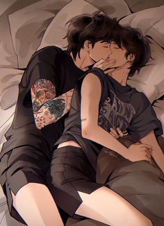 two people laying in bed with tattoos on their arms and legs, one is kissing the other