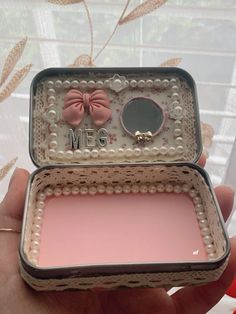 a person holding a small box with pearls and a bow on the lid that says me