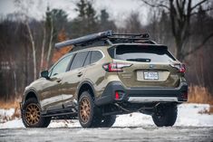 the rear end of a brown and black subarunt parked on snow covered ground