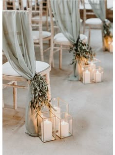 candles are lit in front of chairs with drapes and greenery on the back