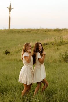 two young women standing in tall grass laughing