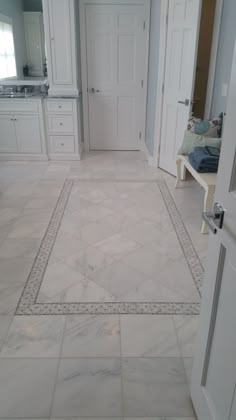 a large bathroom with white cabinets and marble flooring