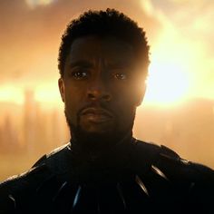 a close up of a person in a suit with the sun shining behind him and clouds