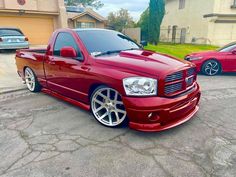 a red truck parked in a parking lot next to other cars