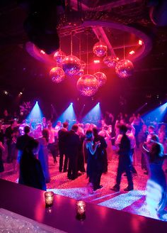 a group of people standing around in a room with disco balls hanging from the ceiling