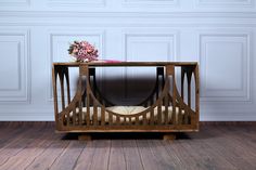 a wooden table with flowers on it in front of a white wall and wood floor