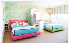 two beds in a room with green and pink wallpaper