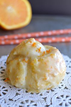 a close up of a doughnut on a doily with an orange in the background