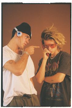 two people standing next to each other with ear buds in their ears and one man pointing at something