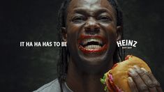 a man with dreadlocks holding a hamburger and saying it has to be heinez