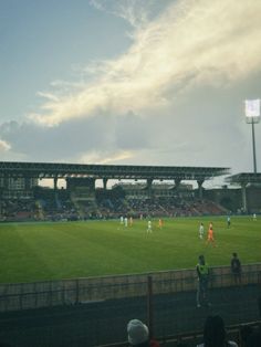 a group of people standing on top of a lush green field next to a soccer field