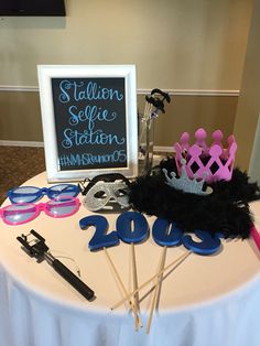 a table topped with lots of items like glasses and a tiara next to a sign