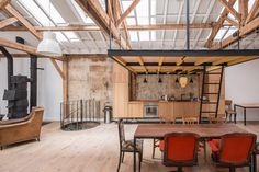 an industrial style kitchen and dining room with wood floors, exposed ceiling beams, wooden furniture, and large windows