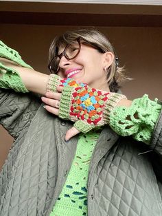 a woman with her hands on her face and wearing knitted fingerless mitts