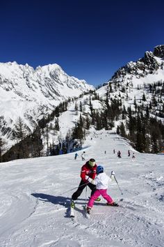 two people on skis in the snow with mountains in the backgroung