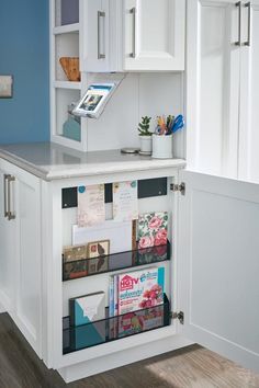 a kitchen with white cabinets and shelves filled with cards, magazines and other office supplies