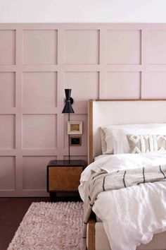 a bedroom with pink walls and white bedding