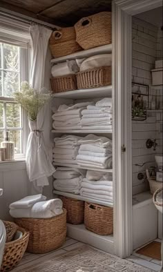 a white bathroom with lots of towels and baskets on the shelves in front of it