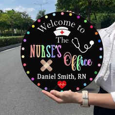 a woman holding up a sign that says welcome to the nurses office