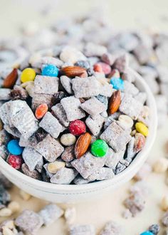 a white bowl filled with cereal and nuts on top of a table next to other candies