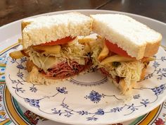 a sandwich cut in half sitting on top of a white and blue flowered plate