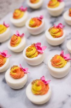 small deviled eggs decorated with pink and yellow decorations